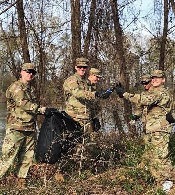 Volunteers putting trash in bag by stream