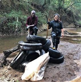 Volunteers in front of river with tires